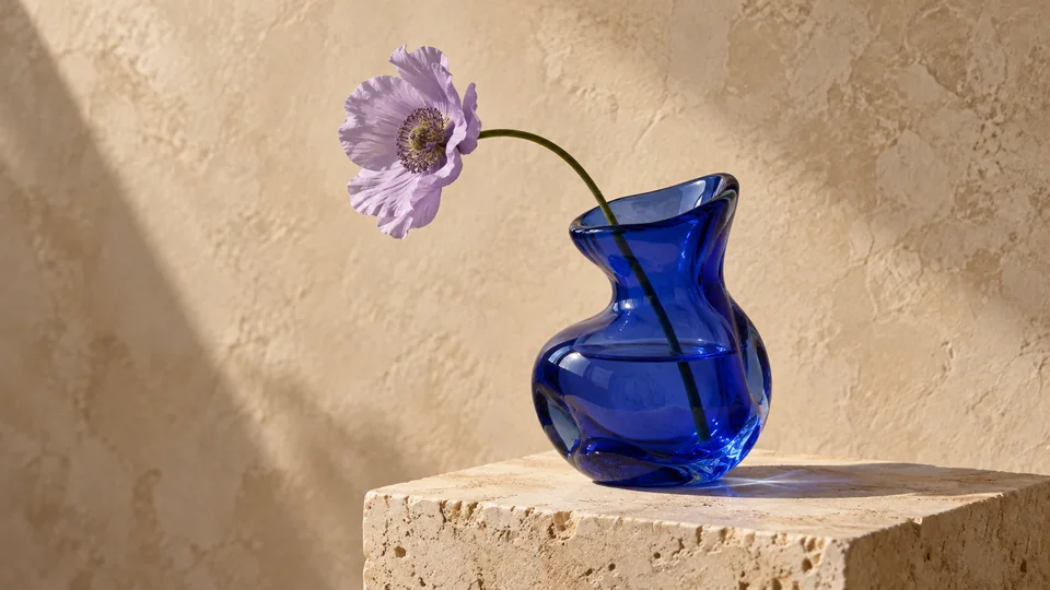 A sculptural cobalt glass vessel and lavender flower on limestone
